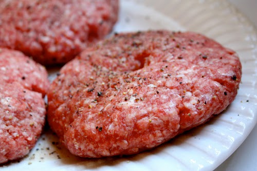 Raw beef hamburger patty seasoned close up photo.