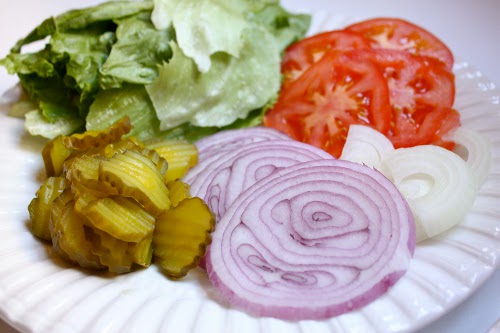 Belag für Hamburger: Zwiebeln, Salat, Gurken und Tomaten.