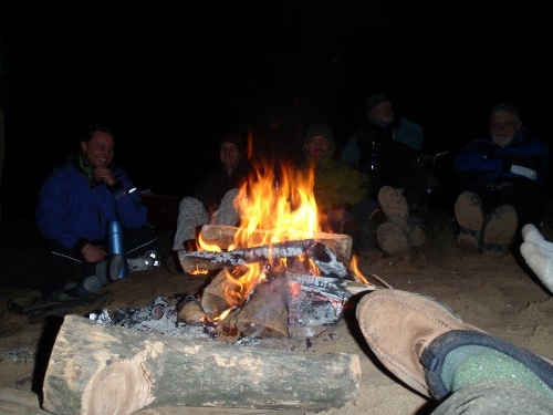 A group of man sitting around a fire.