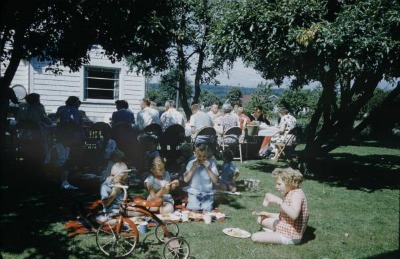 Picnic în aer liber la o petrecere de cartier de epocă și copii care mănâncă împreună.