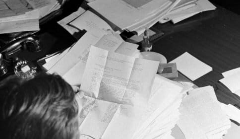 A Congressman sitting at a desk with a lot of papers.
