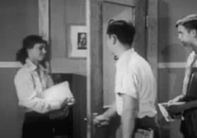 A woman opening a door with a group of people standing in front.