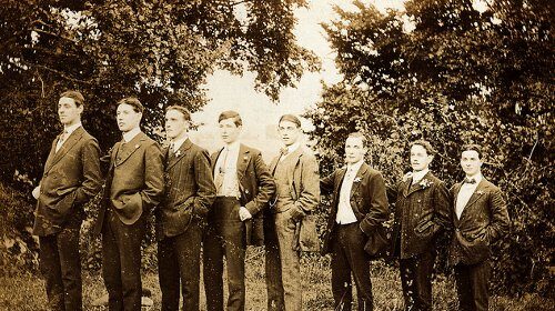 A group of tall men in suits standing in a field.