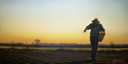 Farmer in field planting seeds by hand dusk.