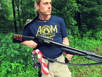 Man carrying shotgun and American bandana.