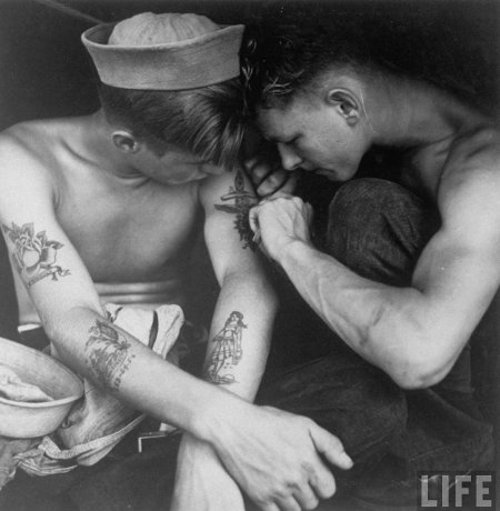 Marins militaires vintage se faisant des tatouages entre eux.