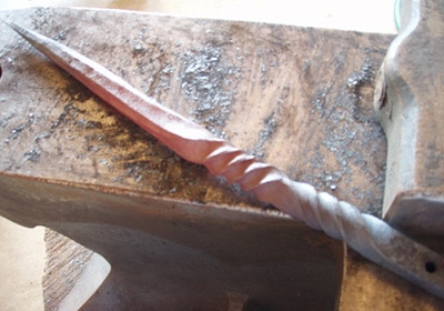 A cone with twisted back placed on an anvil.