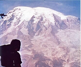 A man is embarking on an ultra-backpacking adventure, skills in hand, standing triumphantly on top of a mountain with a backpack.