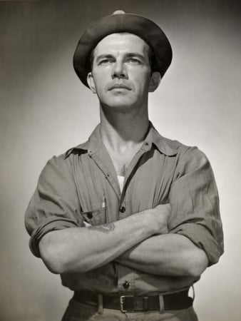 A black and white photo of a working man in a hat, showcasing his stylish dressing.