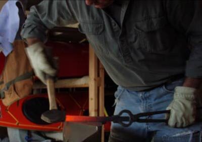 A man blacksmithing in a garage.