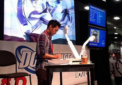 A Comic Book Artist at a table signing a comic book.