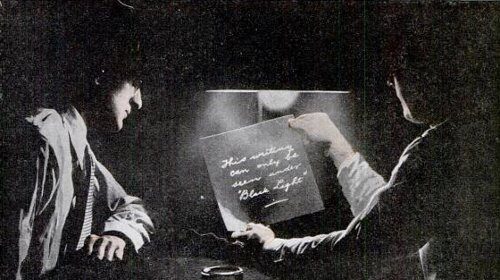 A man is holding a piece of paper and writing with invisible ink.