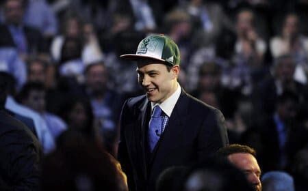 A man in a suit and hat Law smiles in front of a crowd