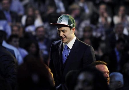 A man in a suit and hat Law smiles in front of a crowd