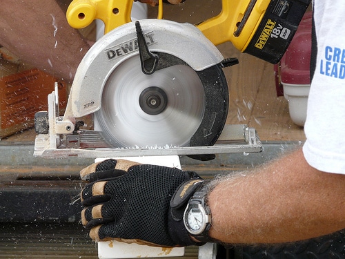 Dewalt circular saw used for cutting wood with protective gloves.