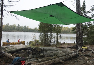 Tarp shelter strung high in trees campsite protection.