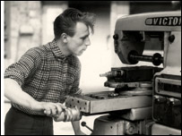 Vintage men using welding machine while shirt sleeves rolled up.