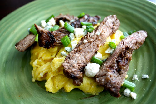 Skirt steak with scrambled eggs, green onion and cheese.