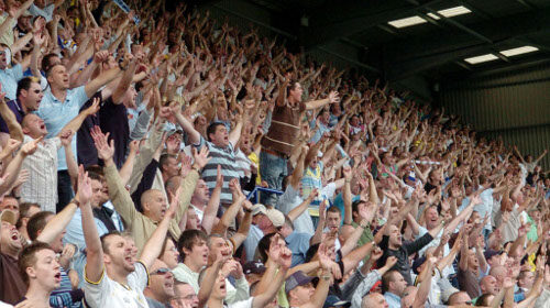 Doers rise in a stadium while viewers watch.