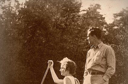 A man and woman standing next to a canoe, holding a canoe paddle.