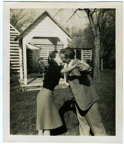 A last romantic embrace between a man and woman in front of a house.
