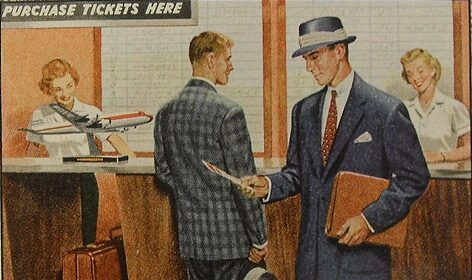 A Traveling Man in a suit and tie is talking to another man in a suit.