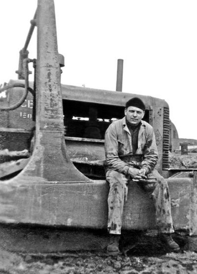 Vintage man blue collar worker sitting on machinery.