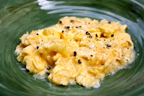 Scrambled eggs finished on plate with pepper. 