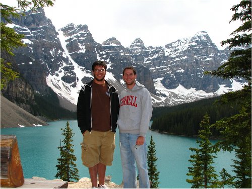 Men posing at lake with mountain.