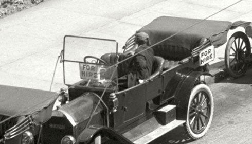 A man skillfully parallel parks his car in a black and white photo.