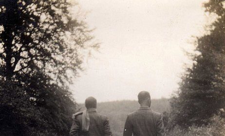 Two men grieving for their deceased friend walk down a country road.