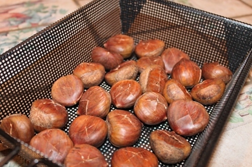 Placing chestnuts in long gazzle pan.