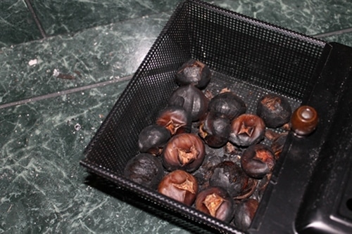 Chestnuts in roasting pan with dark color. 