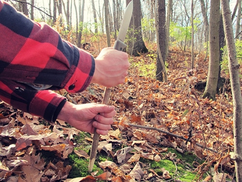 A man digging the ground with stick.