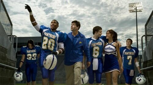 A group of football players showcasing their manliness on a Friday night under the lights in a stadium.