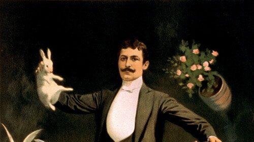 A mature, masculine man in a tuxedo holding flowers.