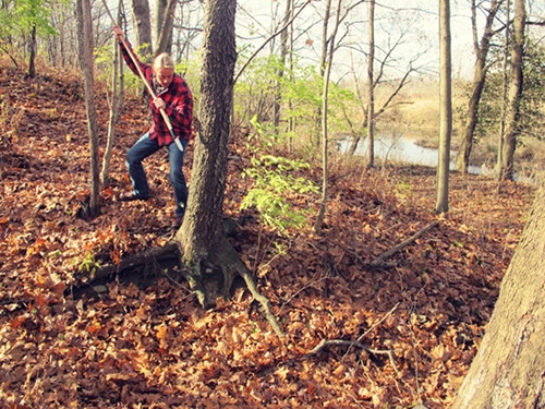 A man pointing hunting weapon toward a tree.