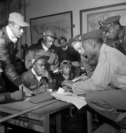 Vintage airmen planning and writing on paper about strategy.