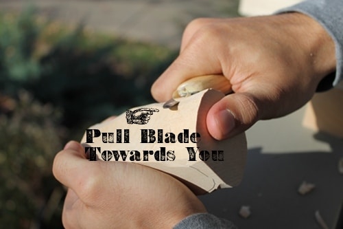 A man applying pull stroke for whittling.