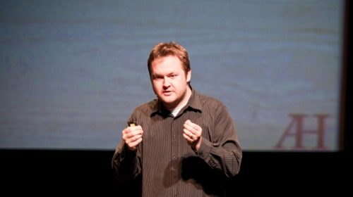 A public speaker passionately raising his fist on stage during his job.