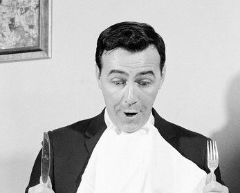 A man sitting at a table with a knife and fork, ready to indulge in a delicious and satisfying meal.