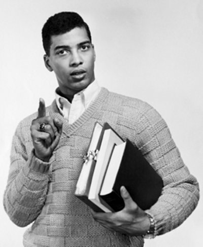 Vintage black American student with books in arms pointing. 