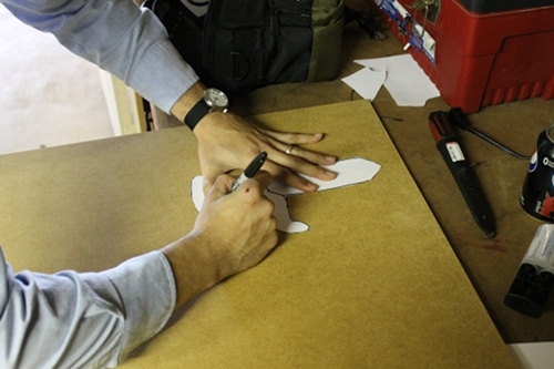 A man tracing pattern of sword on the wooden board.