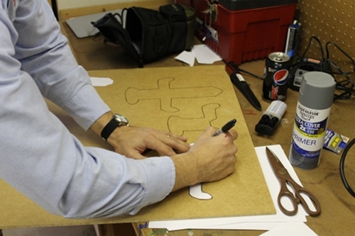 A man tracing two Sword hilts on the board.