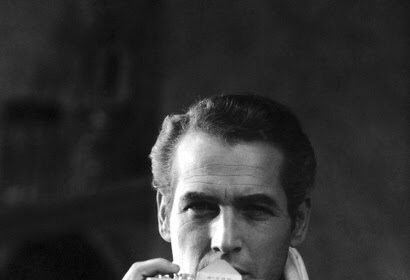 A man in a suit wearing a scarf, capturing a moment with a camera.