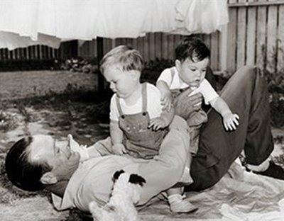 A dad playing with 2 toddlers on the floor