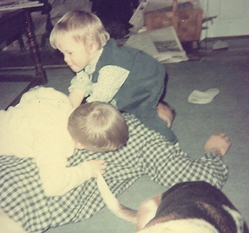 vintage dad roughhousing with 2 kids with dog on the floor besides them. 