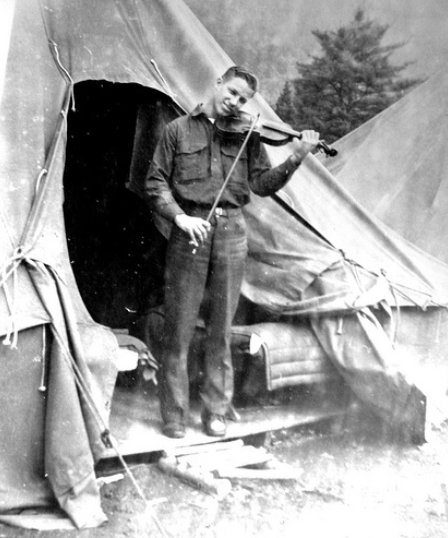 A disciplined man playing a violin in front of a tent.