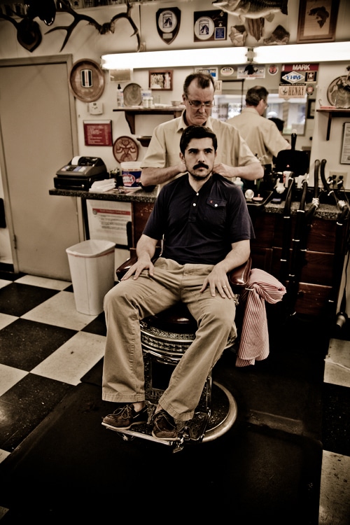 A man sitting at barbershop for hair cut. 