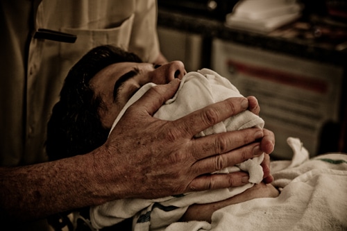 Barber applying warm towel after shaving.